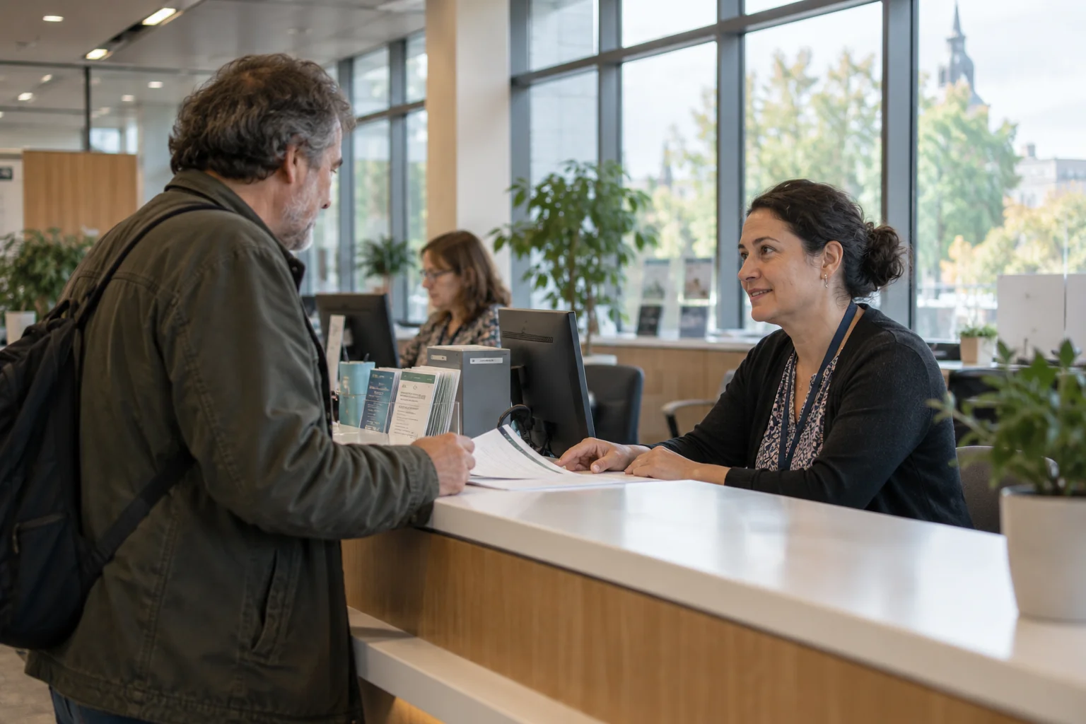 A public service employee helps a visitor at a welcoming civic reception desk.