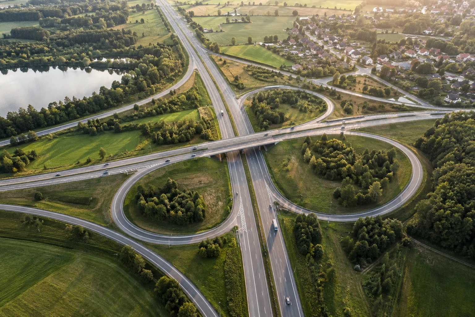 An aerial view shows roads diverging and reconnecting across a green landscape.